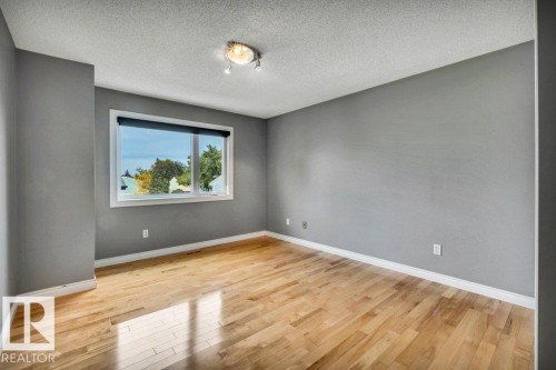 Hardwood-style flooring with a window, track lighting, and neutral wall paint - #24 3811 85 St Nw, Edmonton, AB 