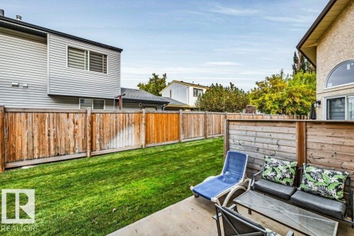 Expansive backyard featuring a manicured lawn, full privacy fencing, and a concrete patio area - #24 3811 85 St Nw, Edmonton, AB 