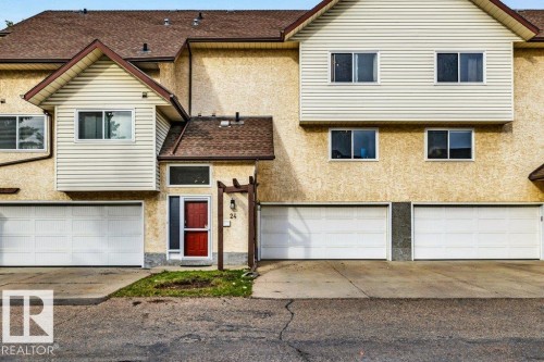 Stucco exterior with brown shingle roofing, white vinyl siding accents, and multiple garage doors - #24 3811 85 St Nw, Edmonton, AB 