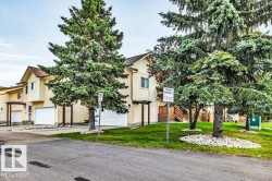 Two-story stucco exterior with white garage doors and a brown shingle roof - 