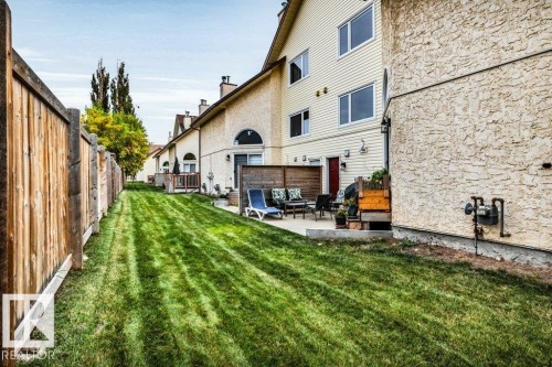 Expansive grassy yard with wood fencing and a concrete patio - #24 3811 85 St Nw, Edmonton, AB 