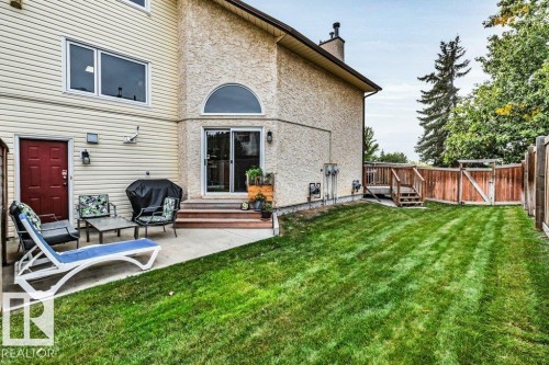 Expansive green lawn, concrete patio, wood fencing, exterior siding, and a rear deck with stairs - #24 3811 85 St Nw, Edmonton, AB 