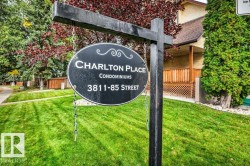 Charlton Place condominiums sign with an expansive lawn, mature trees, and a wooden lattice fence - 