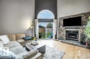 Vaulted ceiling, stone-clad fireplace, wood-finish flooring, sliding glass door, and an arched transom window - #24 3811 85 St Nw, Edmonton, AB 