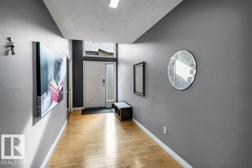 Entryway featuring wood-finish flooring, a white paneled entry door, and a transom window - #24 3811 85 St Nw, Edmonton, AB 
