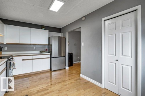 Wood-finish flooring, white cabinetry, stainless steel refrigerator, and recessed ceiling lighting - #24 3811 85 St Nw, Edmonton, AB 