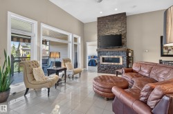 Stone-clad fireplace with a recessed linear firebox, high ceilings, recessed lighting, and large patio doors leading to an exterior balcony - 