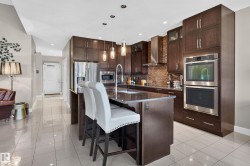 Kitchen featuring dark wood-finish cabinetry, stainless steel appliances, a central island with countertop, and tile flooring - 