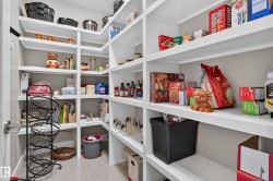 Built-in shelving with multiple storage levels, light-colored flooring, and a white door with a metal handle - 