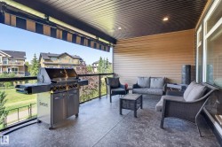 Covered outdoor patio with a patterned concrete surface, glass panel railings, and a horizontal siding exterior wall - 