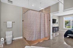 Tiled flooring, shower with tiled walls, white toilet, and towel bar - 