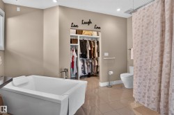 Built-in soaking tub with deck-mounted chrome faucet, recessed lighting, tile flooring, and walk-in closet with shelving and hanging rods - 