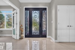 Entryway featuring a decorative wrought iron and glass front door, high ceilings, and light-toned tile flooring - 