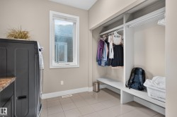 Laundry area featuring tile flooring, a window, and built-in closet storage with hanging rods and shelving - 