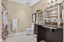 Granite-finish countertop, undermount sink, ceramic tile flooring, subway tile shower surround, and a vanity light fixture - 