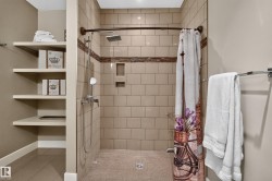 Tiled shower stall with a fixed showerhead, hand-held shower, and recessed shelving - 