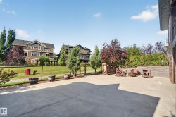 Expansive concrete patio area, integrated retaining wall, mature landscaping, and chain-link fencing - 