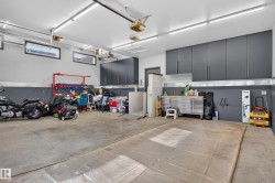 Concrete flooring, multiple overhead lighting fixtures, upper wall-mounted cabinetry, windows with horizontal blinds, and garage door openers - 