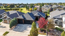 Pitched rooflines, attached double garage, stone and siding exterior, concrete driveway, and mature landscaping - 