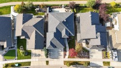 Gabled roofline, mature landscaping, paved driveway, concrete walkways, and an established residential setting - 