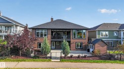 Multi-level property with dark shingle roofing, brown horizontal siding, a second-story balcony with an awning, and a ground-level patio - 