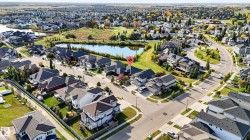Residential neighborhood with paved streets and sidewalks, featuring a prominent pond and established green spaces - 
