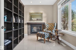 Built-in shelving, tile flooring, fireplace with a tile surround, wood mantel, and large window - 