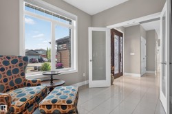 Spacious entryway featuring a decorative glass front door, light-toned tile flooring, and a large picture window - 