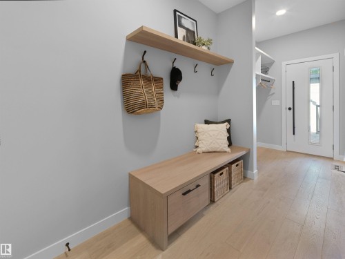 Entryway featuring a built-in wood-finish bench with storage, coordinating floating shelf, and wood-finish flooring - 9118 89 Street Nw, Edmonton, AB 