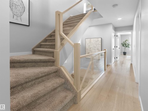 Light wood-finish flooring, carpeted staircase, glass and wood railing, recessed lighting, and white walls - 9118 89 Street Nw, Edmonton, AB 