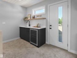 Built-in wet bar with dark cabinetry, white countertop, and stainless steel beverage refrigerator - 