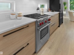 Stainless steel range with red accent knobs, white countertops, wood-finish cabinetry, and light wood-finish flooring - 