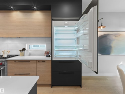 Integrated refrigerator, light wood-finish cabinetry, white subway tile backsplash, white countertops, and wood-finish flooring - 9118 89 Street Nw, Edmonton, AB 