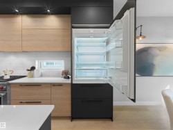 Integrated refrigerator, light wood-finish cabinetry, white subway tile backsplash, white countertops, and wood-finish flooring - 