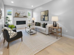 Recessed lighting, light wood-finish flooring, white walls, built-in electric fireplace with white surround, and wood mantel - 