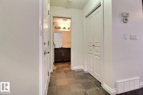 Tiled flooring extending through the hallway, white interior doors with polished hardware, and painted white walls - 5205 168 Avenue Nw, Edmonton, AB 