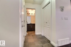 Tiled flooring extending through the hallway, white interior doors with polished hardware, and painted white walls - 