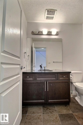 Dark wood-finish vanity with a dark countertop and integrated sink - 5205 168 Avenue Nw, Edmonton, AB 