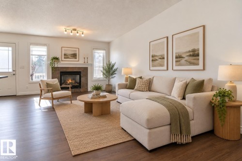 Spacious living area featuring wood-finish flooring, a tiled fireplace with a mantel, multiple windows, and a vaulted ceiling - 5205 168 Avenue Nw, Edmonton, AB 