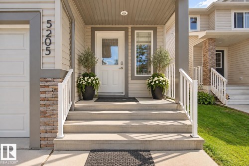 Covered entrance with concrete steps and white railings - 5205 168 Avenue Nw, Edmonton, AB 
