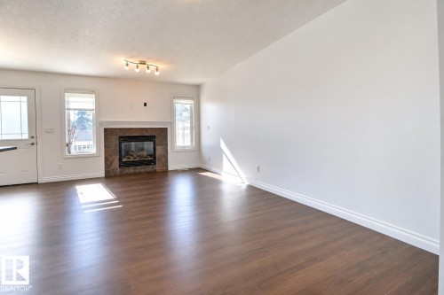 Wood-finish flooring, white walls, and a tiled fireplace with a white mantel - 5205 168 Avenue Nw, Edmonton, AB 