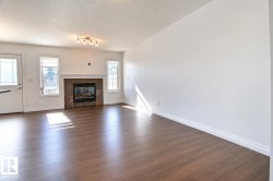 Wood-finish flooring, white walls, and a tiled fireplace with a white mantel - 