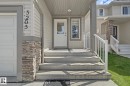 Front entry with concrete steps, white railings, and stacked stone accents - 5205 168 Avenue Nw, Edmonton, AB 
