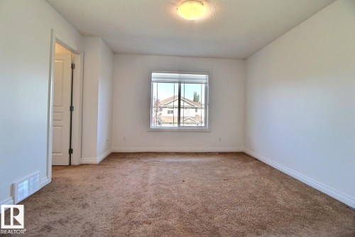 Neutral wall color with a framed window, flush mount lighting, and broadloom carpeting - 5205 168 Avenue Nw, Edmonton, AB 