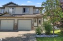 Two-story exterior with light gray siding, stone accents, two garage doors, a front entry door with sidelight, and a concrete driveway - 5205 168 Avenue Nw, Edmonton, AB 