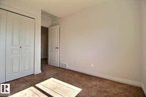 Built-in bi-fold closet, paneled interior door, and neutral carpeting - 5205 168 Avenue Nw, Edmonton, AB 