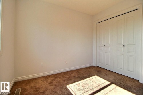 Neutral wall color, wall-to-wall carpeting, bi-fold closet doors with panel detailing, white trim - 5205 168 Avenue Nw, Edmonton, AB 