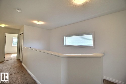 Upper-level landing featuring a half-wall railing, horizontal window with blinds, and flush-mount lighting fixtures - 5205 168 Avenue Nw, Edmonton, AB 