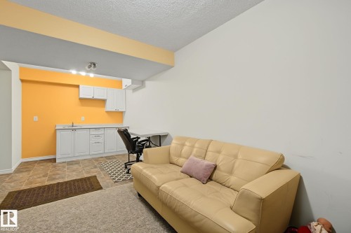 Lower level space featuring ceramic tile flooring, white cabinetry, a built-in sink, and track lighting - 5205 168 Avenue Nw, Edmonton, AB 