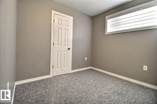 Neutral wall paint, white trim, white paneled door, gray textured carpet, and a horizontal window with blinds - 5205 168 Avenue Nw, Edmonton, AB 